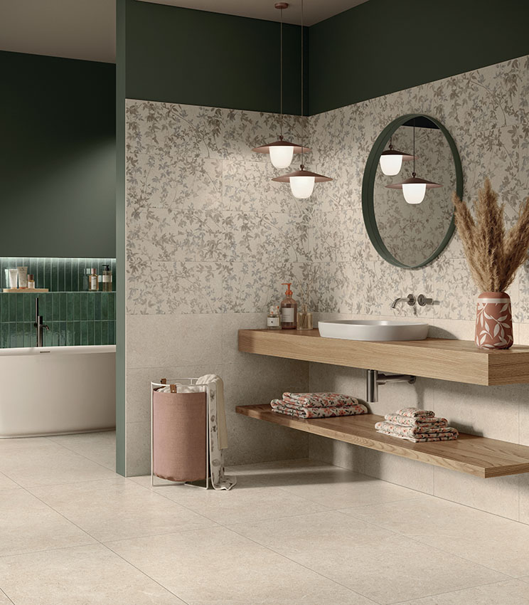 Bagno contemporaneo con superfici delle collezioni Surround Sketch, Sketch Impressions, Sketch Soft e Workshop Jade, caratterizzato da rivestimenti floreali nei toni neutri, pareti verde scuro, lavabo bianco su mensola in legno, specchio rotondo e vasca freestanding visibile sullo sfondo.