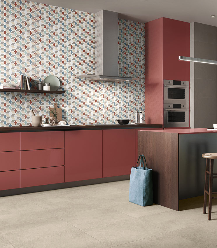 Cucina contemporanea con superfici delle collezioni Even Dove, Optical Terzofuoco e Context Square, caratterizzata da un rivestimento geometrico multicolore, mobili color terracotta, piano di lavoro scuro, isola centrale e pavimento chiaro.