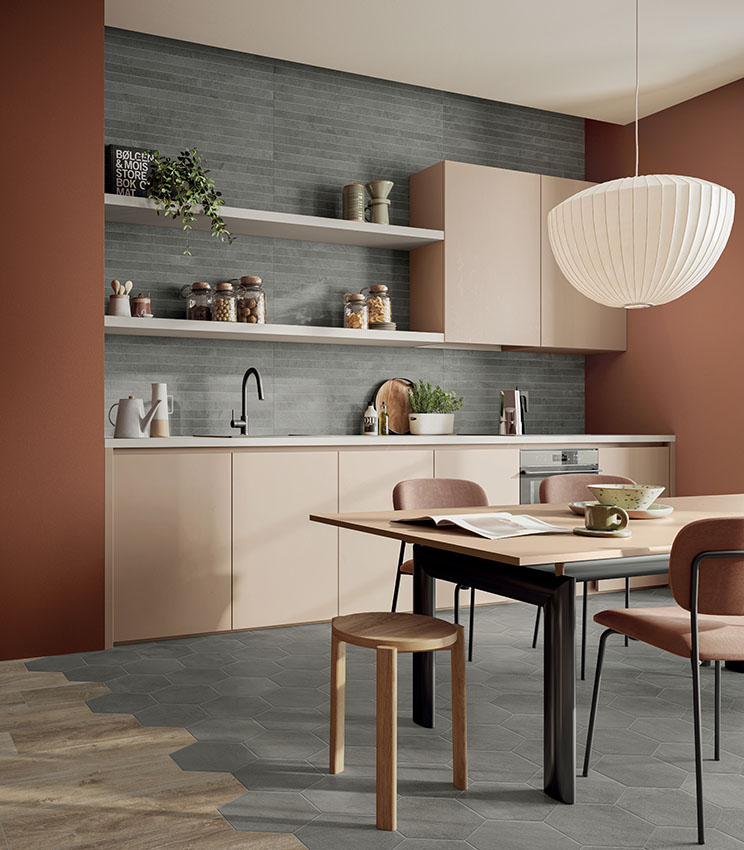 Vista frontale di parete lavabo rivestita con listelli di gres porcellanato effetto pietra, specchio tondo e lavabo esterno rosso.