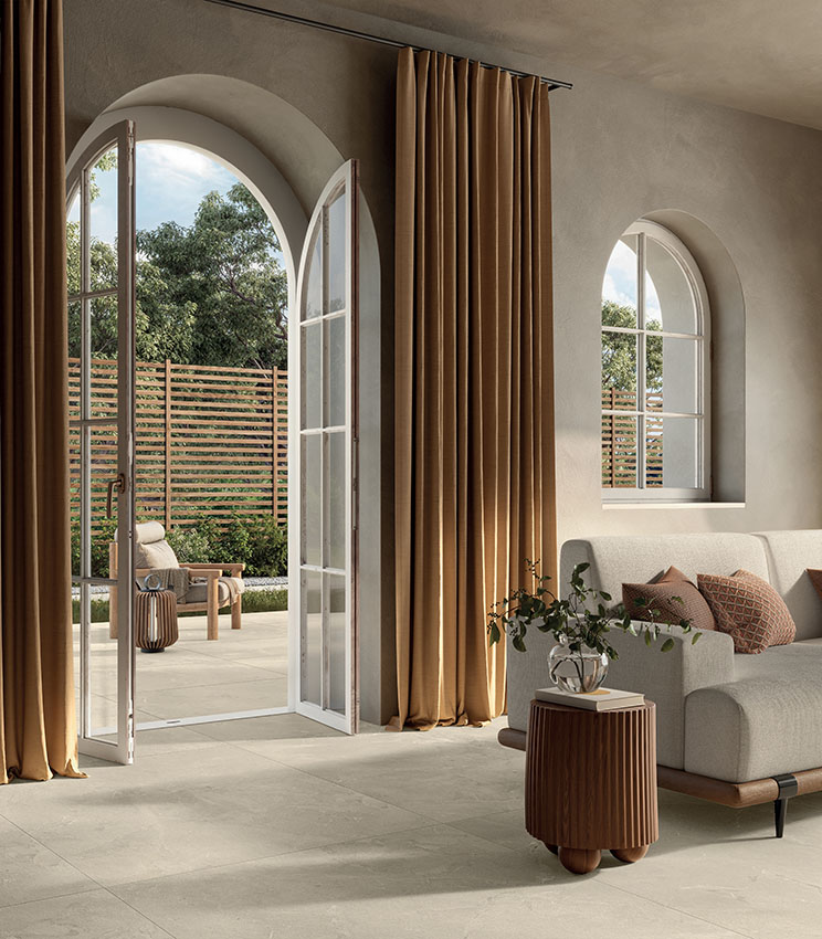 Living contemporaneo con pavimento in gres porcellanato effetto pietra, tonalità naturali e ampie aperture verso l’esterno per un ambiente elegante e luminoso.
