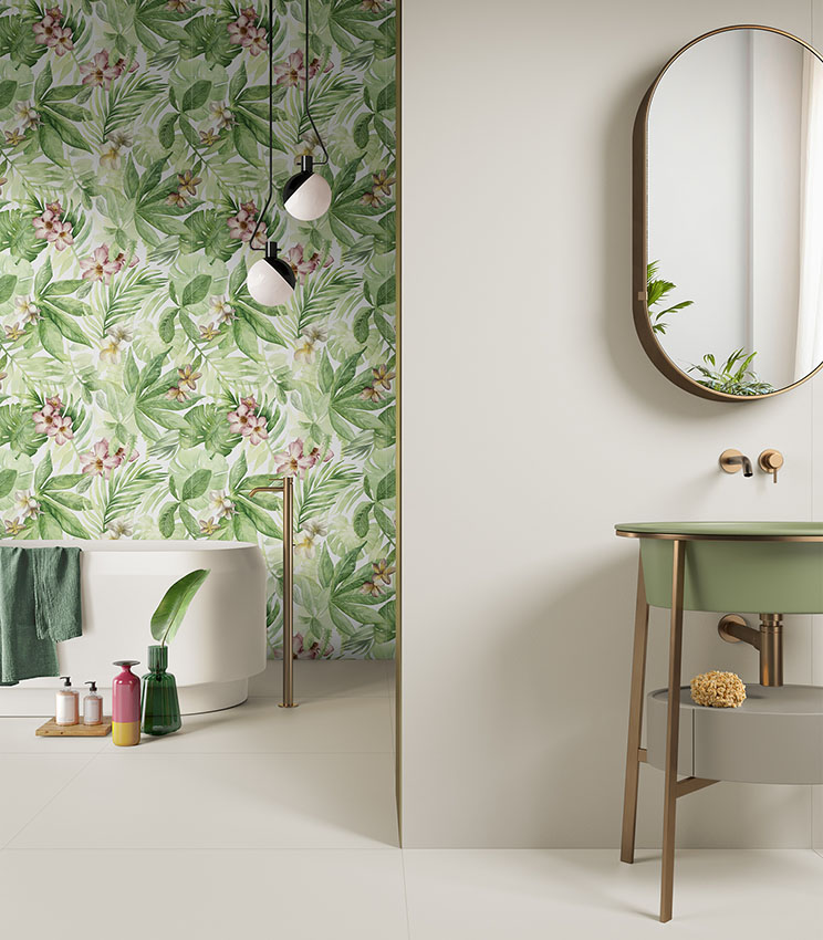 Bagno moderno con parete decorata a motivi tropicali, vasca freestanding bianca e lavabo verde con specchio ovale.