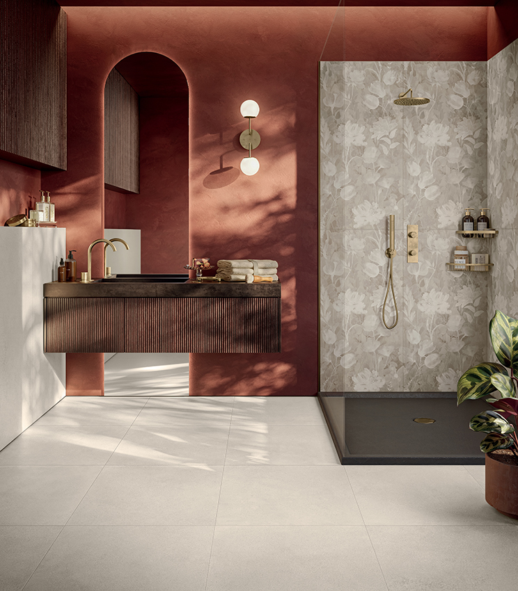 Bagno contemporaneo dal carattere caldo e materico, con pavimento e rivestimenti della collezione Formula di Panaria Ceramica. La superficie Form Cotton Naturale definisce la base neutra dell’ambiente, mentre il decoro floreale Garden Naturale caratterizza la zona doccia, creando un raffinato contrasto con le pareti color terracotta e gli arredi scuri.