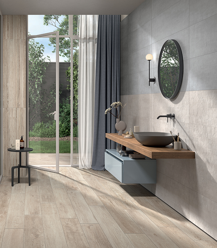 Moderna stanza da bagno dalle tinte chiare e naturali, con pavimento e doccia in gres porcellanato effetto legno, e con un rivestimento strutturato che esalta le qualità materiche della ceramica pigmentata.