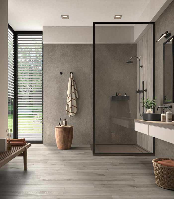 Moderna stanza da bagno pavimentata con doghe di gres porcellanato effetto legno grigio e rivestimento con gres effetto pietra grigio. Collezione Borealis di Panaria Ceramica.