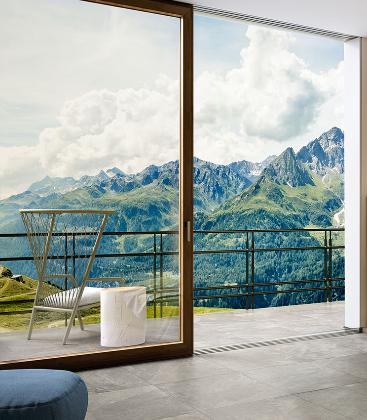 Vista raso pavimento di pavimentazione esterna e porta finestra di una stanza da letto. Pavimenti esterno e interno abbinati tra loro, in gres porcellanato effetto pietra di colore grigio