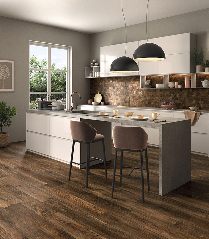 Cucina bianca moderna con isola dinette, pavimento in doghe scure di gres porcellanato effetto legno e backsplash in mosaico ceramico esagonale coordinato