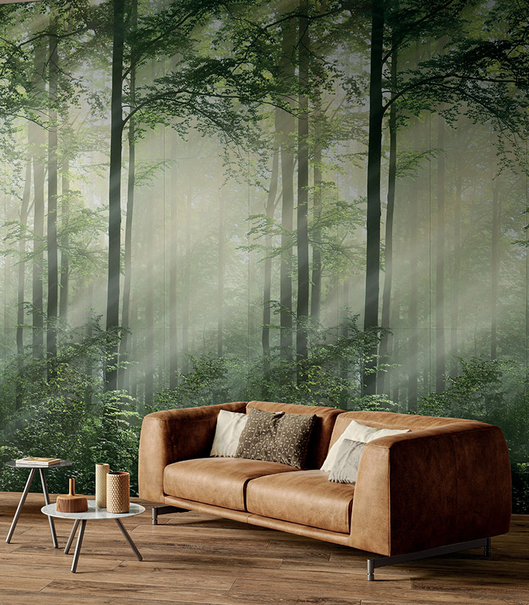Living con divano  in pelle e scenografico rivestimento ceramico in lastre sottili effetto wallpaper raffigurante, con realismo fotografico, un bosco