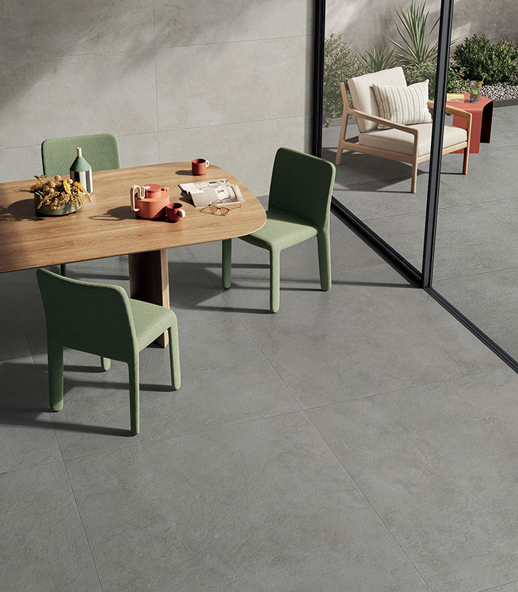 Sala da pranzo luminosa con pavimento in gres effetto cemento La Matière di Panaria Ceramica, coordinato con l’outdoor.