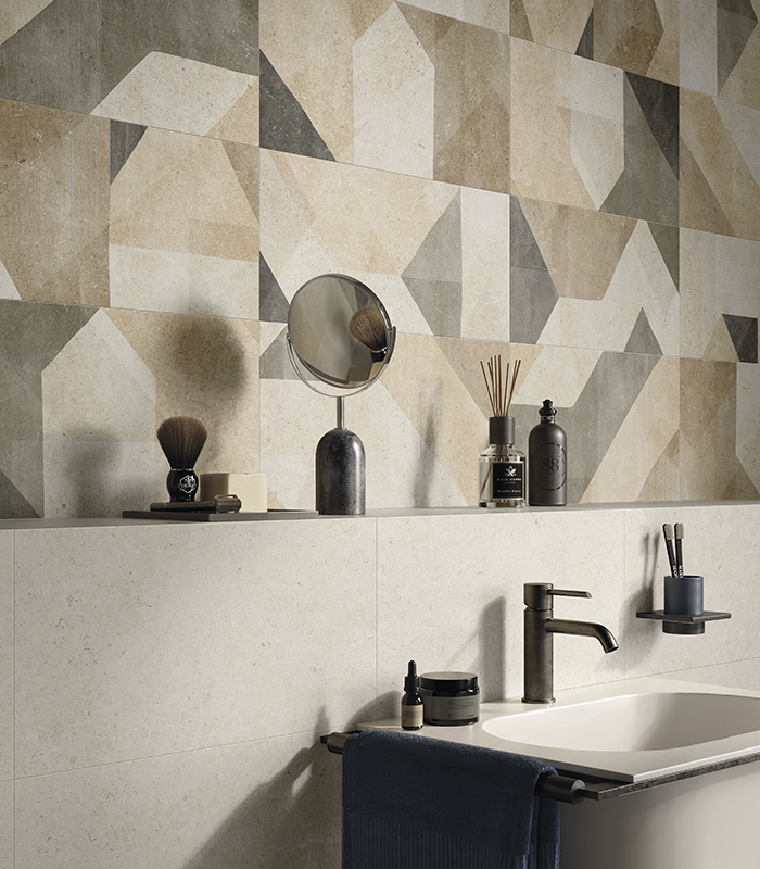 Parete lavabo di un bagno piccolo in gres effetto pietra chiaro, con mensola a 120 cm di altezza e piastrelle decorative multicolor a motivi geometrici