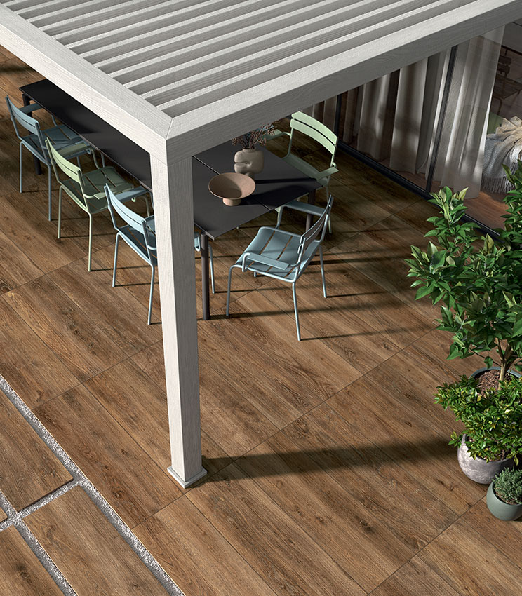 Patio esterno con pavimentazione in gres porcellanato effetto legno, arredi contemporanei e pergola, per uno spazio accogliente, resistente e naturale.
