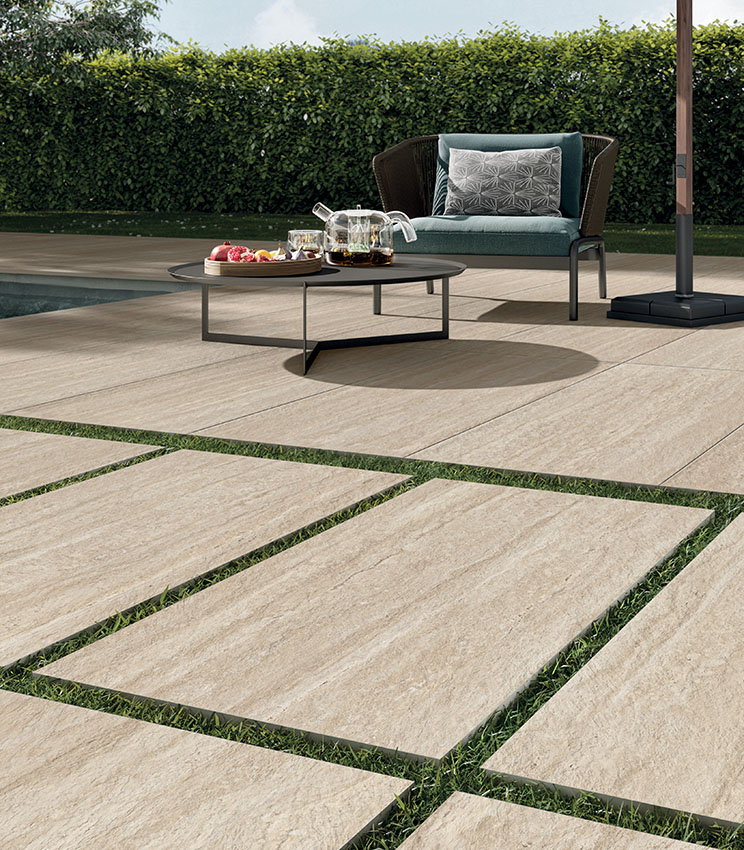 Veduta quasi rasoterra di pavimentazione outdoor in gres 20 mm effetto travertino antistante a una piscina | Collezione Perpetual Travertino di Panaria Ceramica
