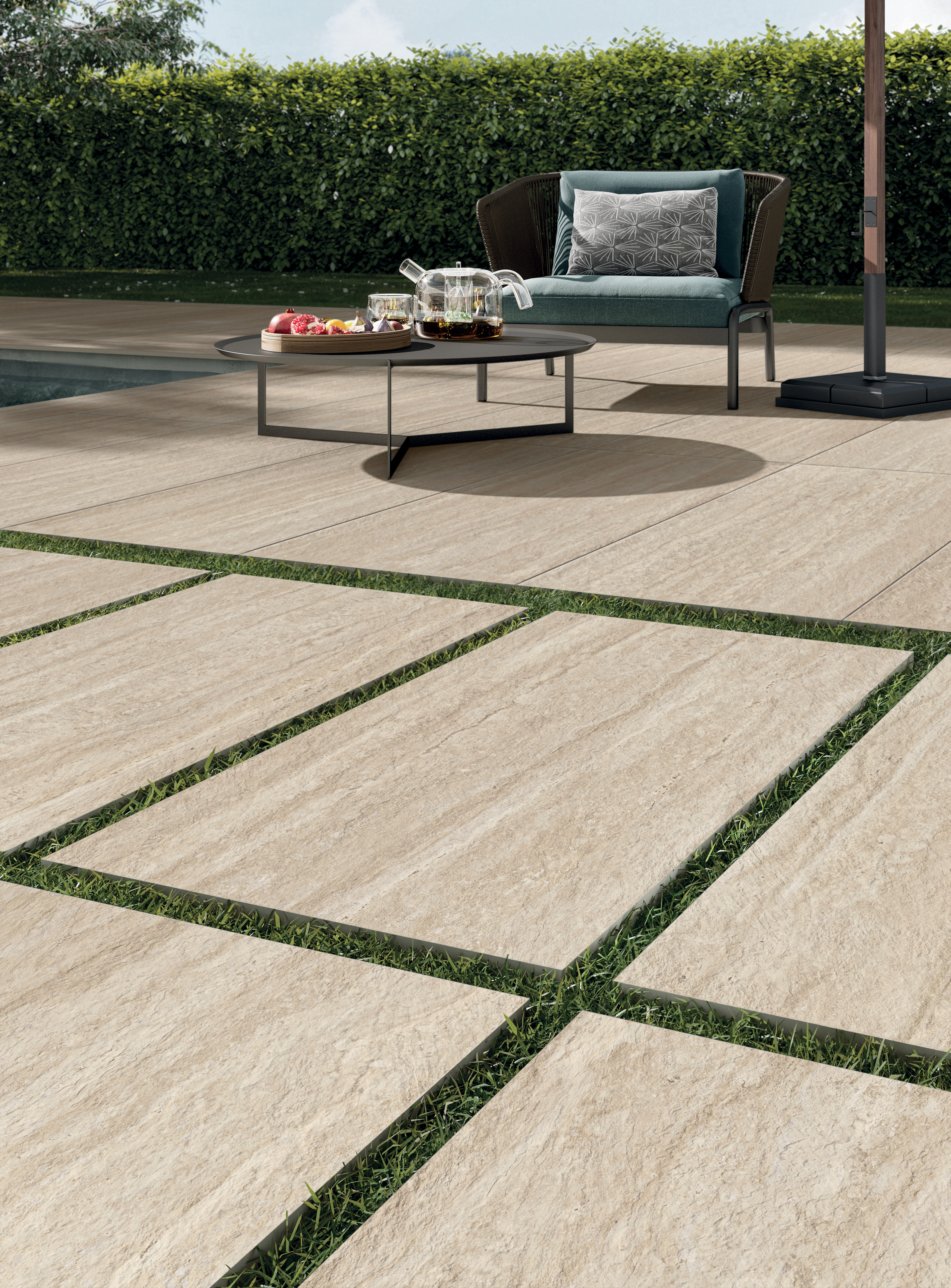 Veduta quasi rasoterra di pavimentazione outdoor in gres 20 mm effetto travertino antistante a una piscina | Collezione Perpetual Travertino di Panaria Ceramica