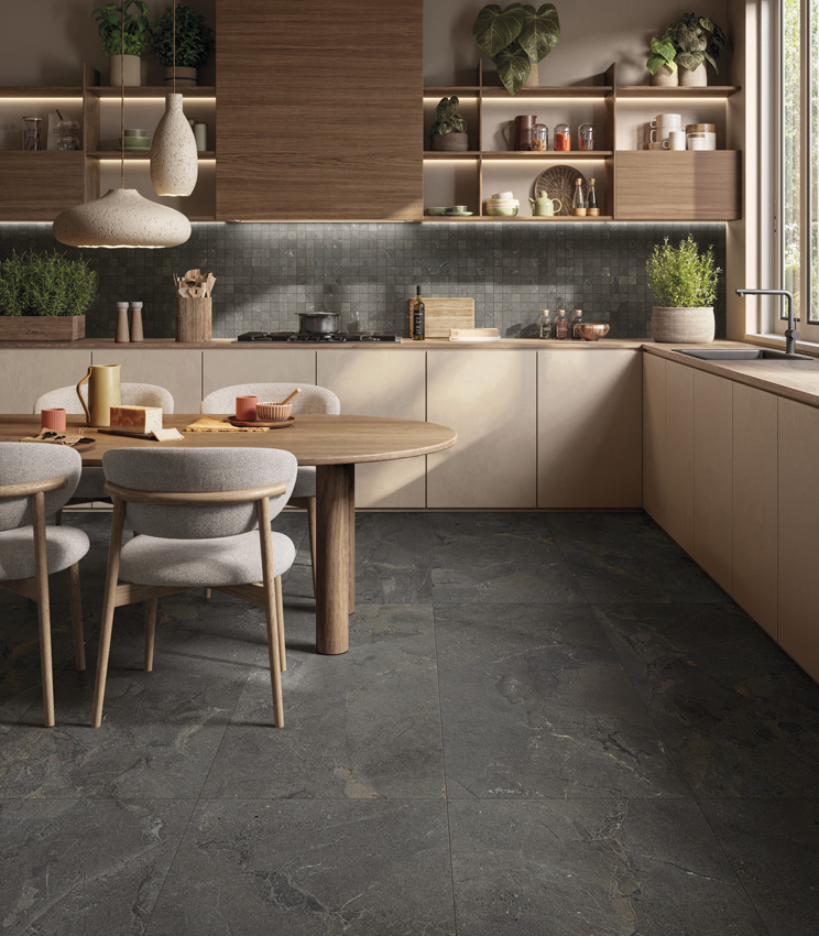 Moderna cucina dai toni caldi con numerose piante verdi in vaso, pavimento in gres porcellanato effetto pietra di colore scuro e backsplash in mosaico ceramico.
