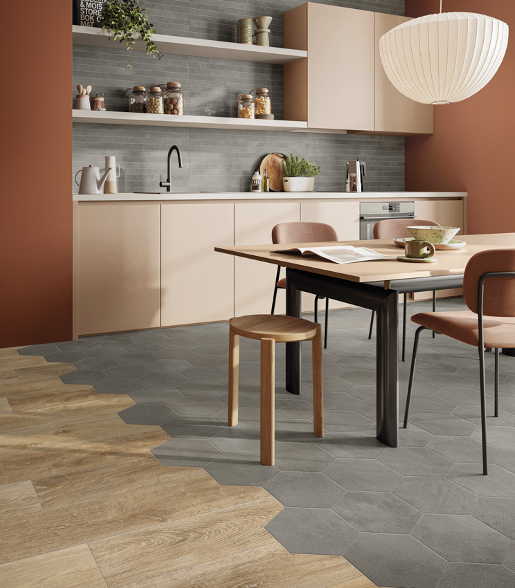 Scorcio di cucina moderna con pareti tinteggiate color mattoni e mobili cipria, backsplash in listelli di gres porcellanato effetto cemento grigio e pavimento multi-effetto, cemento ceramico formato esagonale e doghe di gres porcellanato effetto legno.