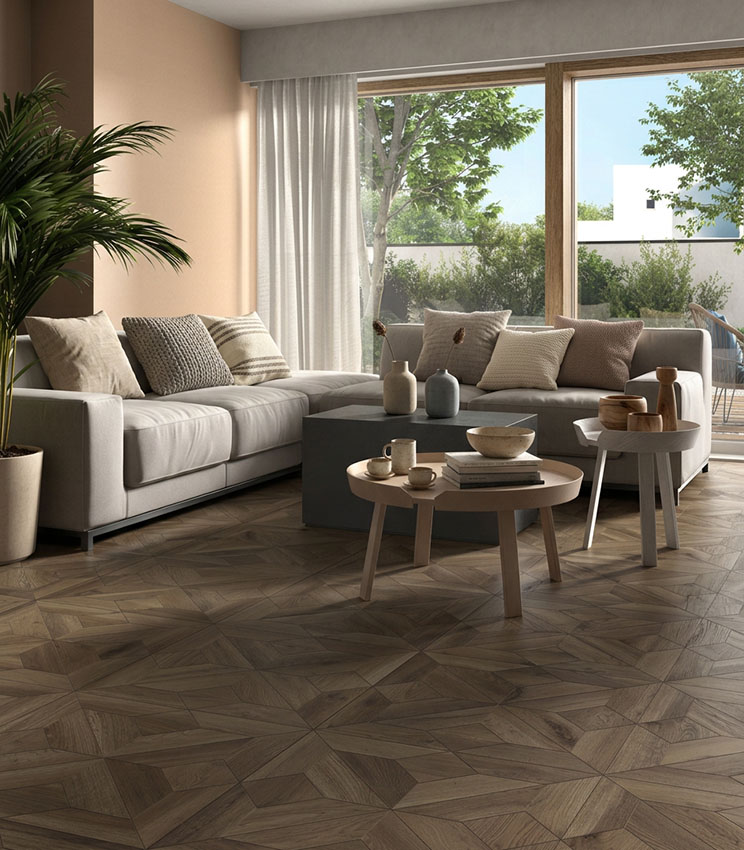 Soggiorno contemporaneo con pavimento della collezione Borealis Donegal Baroque, caratterizzato da una posa geometrica effetto legno, ampio divano chiaro, tavolini bassi, tonalità neutre e grandi vetrate affacciate sul verde.