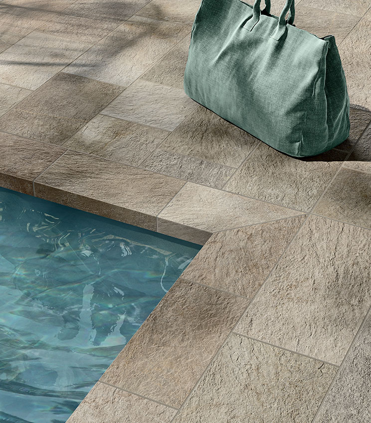 Dettaglio del bordo piscina rivestito in gres porcellanato effetto pietra, con texture materica e tonalità naturali per un risultato elegante e resistente.